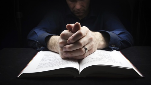A man praying over his Bible.